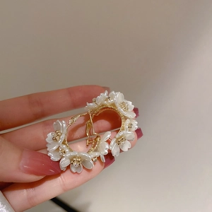 Detailed view of gold plated hoop earrings featuring 3D white flower petal embellishments
