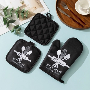 Set da cucina nero in 3 pezzi con guanto da forno e presine su un tavolo azzurro