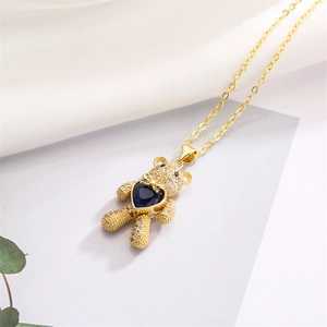 Detail der beweglichen Gold-Teddybär-Kette mit blauem Herz-Zirkon auf Seidenstoff