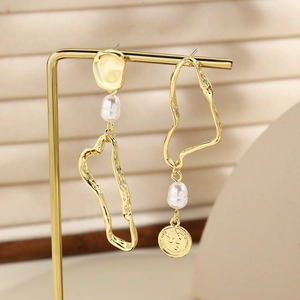 Detail view of gold asymmetric earrings featuring baroque pearls and a queen coin pendant