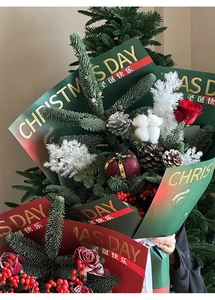 Close-up of gold-stamped Christmas gift wrap with red roses, pine cones and cotton