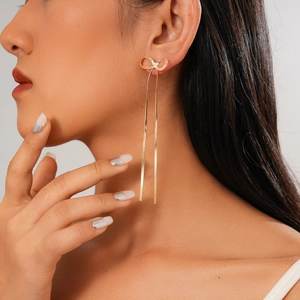 Elegant gold bow earrings with crystal tassel details shown on a model side profile
