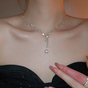 Close-up of diamond-studded flower pendant necklace and matching ring on model