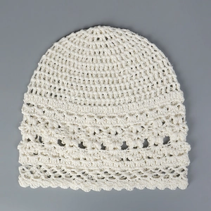 Primer plano del delicado patrón calado de este gorro de lino crema tejido a mano.