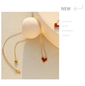 Detailed close-up of a red heart pendant necklace with gold chain and lobster clasp