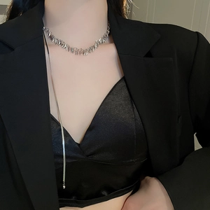 Detail of silver choker necklace with leaf sequins and long tassel on a black outfit