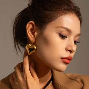 Polished golden heart pendant earrings shown on model for a trendy vintage style