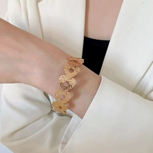 Detail view of gold tiered cutout bracelet with hammered texture on a model wrist