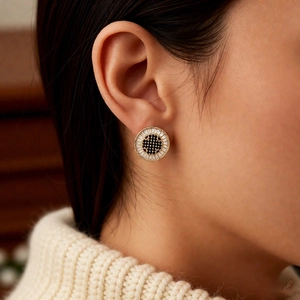 Detail of 18k gold plated round stud earring with black center and white crystals