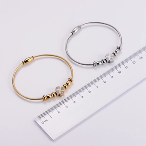 Detail of steel wire clover bangles in gold and silver showing size measurement with a ruler