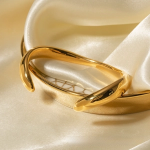 Dettaglio del bracciale rigido in acciaio inossidabile dorato 18k su seta champagne