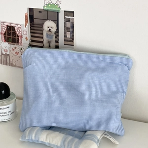 Detailed view of sky blue checkered cotton pouch with zipper in a lifestyle setting