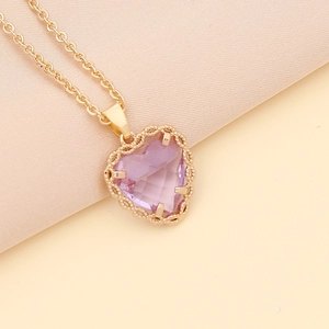Golden chain necklace featuring a delicate purple heart-shaped gemstone pendant on pink silk