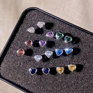 Macro view of eight pairs of colorful heart-shaped zircon earrings in a display box