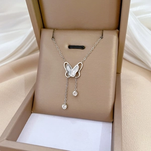 Detail view of a hollow butterfly necklace with shell wings and rhinestone tassels
