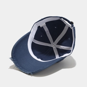 Distressed navy blue cotton baseball cap showing internal structure and 100% cotton label