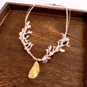 Ethnic woven rope necklace with golden shell pendant and decorative beads on wood background