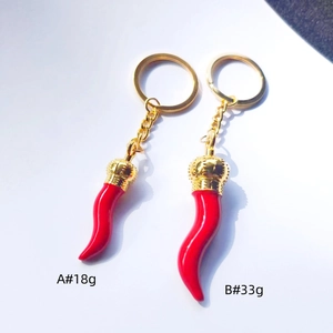 Detail showing two red chili cornicello charms with golden crowns and metal rings