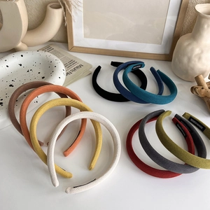 Multiple colorful corduroy headbands in retro shades arranged on a white surface