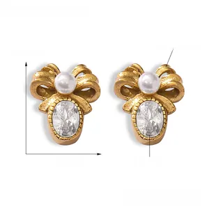 Detail of gold bow earrings featuring an oval zircon and white pearl on titanium steel