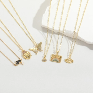 Detail view of gold butterfly, shell, and rainbow pendants on minimalist fine necklaces