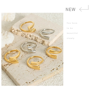 Minimalist spiral wrap rings in gold and silver finish displayed on stone surface