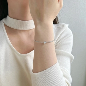 Macro shot of silver heart-shaped diamond bracelet on female wrist showing sparkling stones