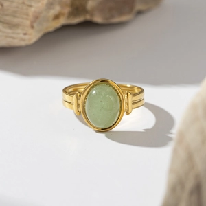 Macro shot of vintage gold-plated titanium ring with an oval light green natural stone