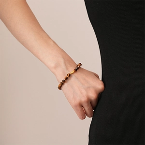 Detail of tiger eye bead bracelet with golden olive bead worn by a model on wrist