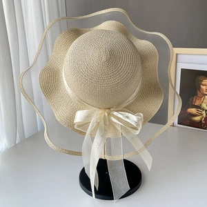 Beige straw sun hat with large wavy mesh brim and ribbon bow for beach vacation