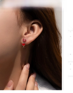 Detailed view of S925 silver long drop earrings with three red enamel hearts on model
