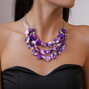 Detail of bohemian triple-layer purple beaded shell necklace with silver metal accents