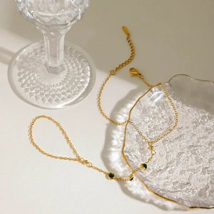 Gros plan d'un bracelet chaîne doré avec trois pierres de zircon vert sur verre