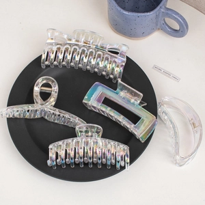 Iridescent laser hair clips in various shapes displayed on a minimalist table