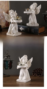 Close-up of a vintage angel resin candle holder with a clear glass cup on a wooden table