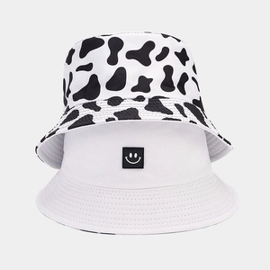 Detail of cow print and white smiley face bucket hats showing cotton twill fabric texture