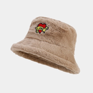 Détail d'un chapeau bob beige en peluche avec fourrure douce et écusson cœur LOVE