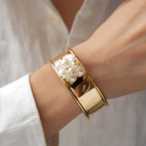Detailed view of wide gold metal cuff bracelet with elegant white pearl flower clusters