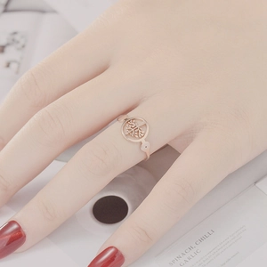 Close-up of rose gold Tree of Life open ring on finger with soft aesthetic background