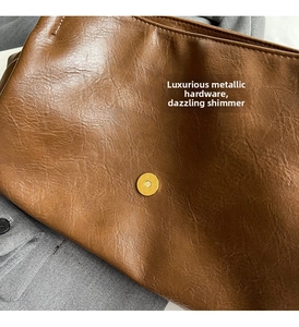 Close-up of brown faux leather bag featuring a gold magnetic closure and fine stitching