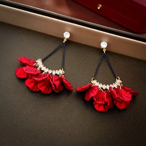 Macro detail of red layered petal earrings with sparkling rhinestones and black tassels