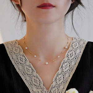 Close-up of elegant gold wave necklace with natural freshwater pearls on a model neck