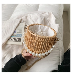 Detail of straw bucket bag with white pearl handle and gold chain strap close-up