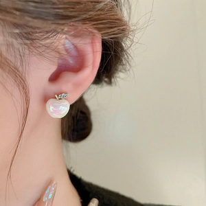 Close-up of apple stud earring with pearlescent finish and crystal leaves on ear