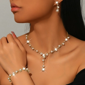 Elegant gold pearl jewelry set including necklace, earrings and bracelet on model