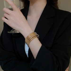 Macro detail of multi-layered gold coiled spiral bracelet on a black suit sleeve