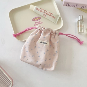 Detail of pink floral drawstring bag with white label on a cozy desktop display