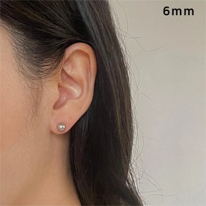 Close-up of a 6mm silver grey pearl stud earring worn on earlobe for size reference