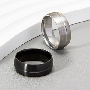 Minimalist 8mm matte black and silver brushed stainless steel rings on a modern pedestal