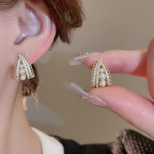 Elegant gold drop earrings with pearls and cubic zirconia on model in warm light